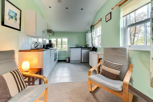 a kitchen with green walls and two chairs and a table at Swallow Cottage at Duffryn Mawr Cottages in Hensol