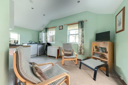 a living room with two chairs and a kitchen at Swallow Cottage at Duffryn Mawr Cottages in Hensol