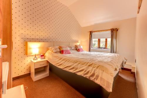 a bedroom with a bed and a window at Swallow Cottage at Duffryn Mawr Cottages in Hensol