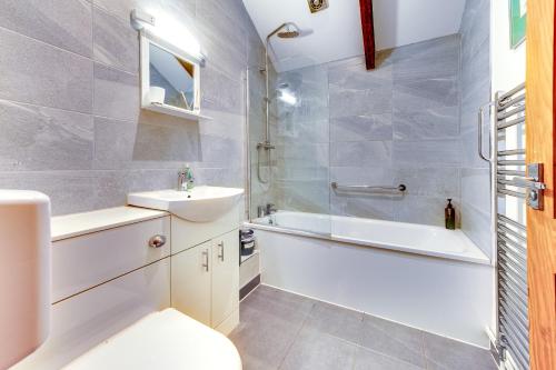 a bathroom with a sink and a tub and a toilet at Swallow Cottage at Duffryn Mawr Cottages in Hensol