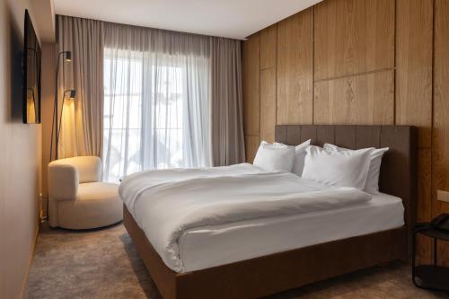 a bedroom with a bed and a chair and a window at MontiSio Boutique Hotel in Gudauri