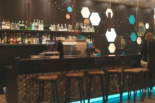 a bar with stools in front of a counter with a bartender at Motel One London-Tower Hill in London