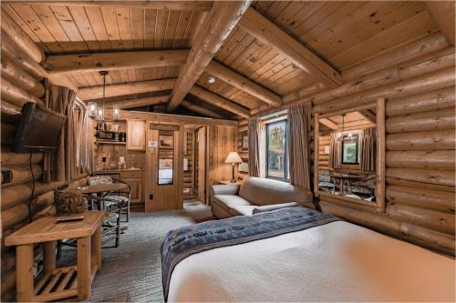 a bedroom in a log cabin with a bed and a desk at Cowboy Village Resort in Jackson
