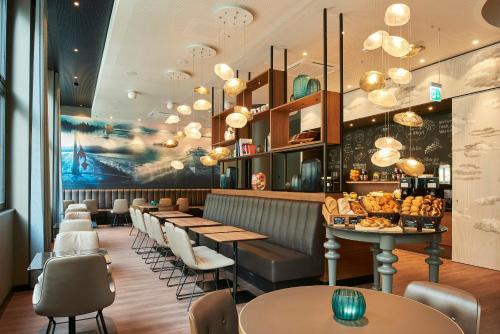 a restaurant with a row of tables and chairs at Motel One Zürich in Zurich