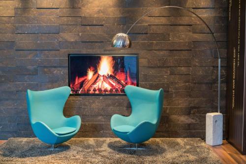 two blue chairs sitting in front of a fireplace at Motel One Leipzig-Nikolaikirche in Leipzig