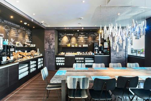 a restaurant with a table and chairs and a bar at Motel One Basel in Basel