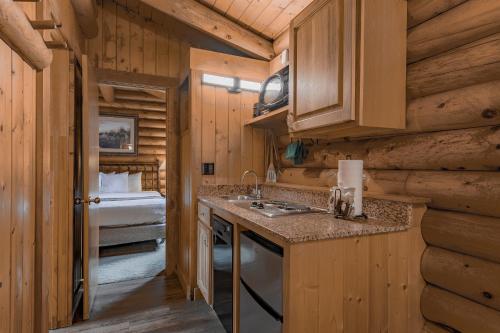 a kitchen in a log cabin with a sink and a bed at Cowboy Village Resort in Jackson
