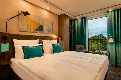 a hotel room with a large bed and a window at Motel One Köln-Neumarkt in Cologne