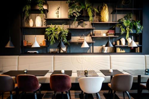 a restaurant with tables and chairs and plants at Motel One Karlsruhe in Karlsruhe