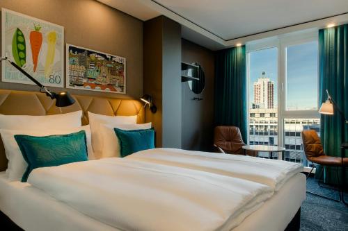 a hotel room with a large bed and a large window at Motel One Leipzig-Post in Leipzig
