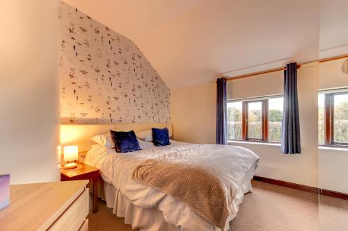 a bedroom with a large bed with blue pillows at Kingfisher Cottage at Duffryn Mawr Cottages in Hensol