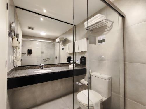 a bathroom with a toilet and a sink and a mirror at Holiday Inn Fortaleza by IHG in Fortaleza