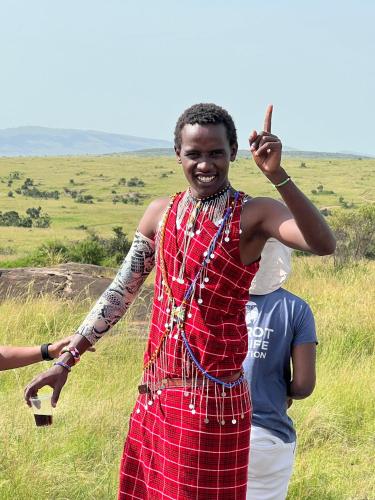a man in a red dress standing in a field at leyianmaasaisafaris in Narok
