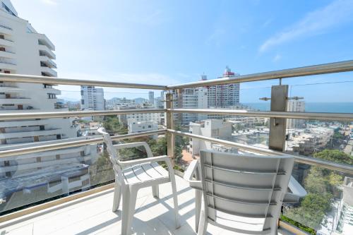 two chairs on a balcony with a view of the city at Hotel Marco Polo Rodadero in Santa Marta
