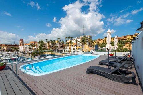 a swimming pool with lounge chairs next to a building at Marina Cabo Plaza "Casa Pura Vida" 108A in Cabo San Lucas