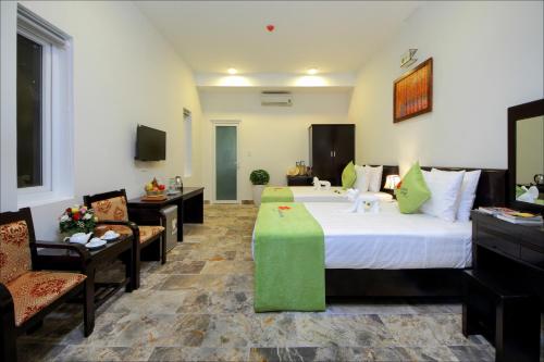 a hotel room with a large bed and two chairs at Lucky Leaf Hoian Villa in Hoi An