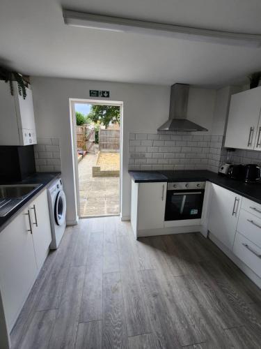 a kitchen with white cabinets and a door to a yard at Ensuite premier rooms in Basildon