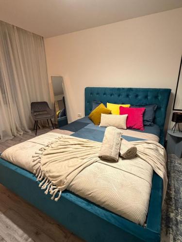 a bed with a blue head board with colorful pillows at GZP Residence Lugoj 19 in Lugoj