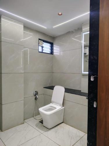 a white toilet in a bathroom with a window at Hotel Red Rose in Vadodara