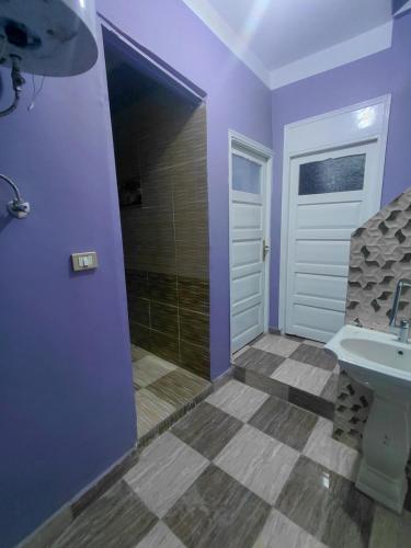 a bathroom with purple walls and a sink and a shower at moon guest house in Aswan
