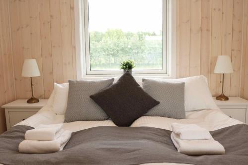 a bedroom with a bed with pillows and a window at Miðhraun - Lava resort & Restaurant in Midhraun