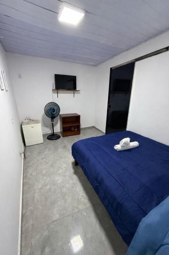 a bedroom with a blue bed and a flat screen tv at Suíte Brisa Mar Saquarema in Saquarema