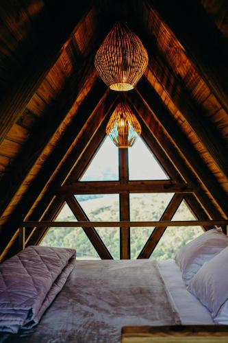 a bedroom with a large window in a attic at Olivas Eco Chalé in Pouso Alto