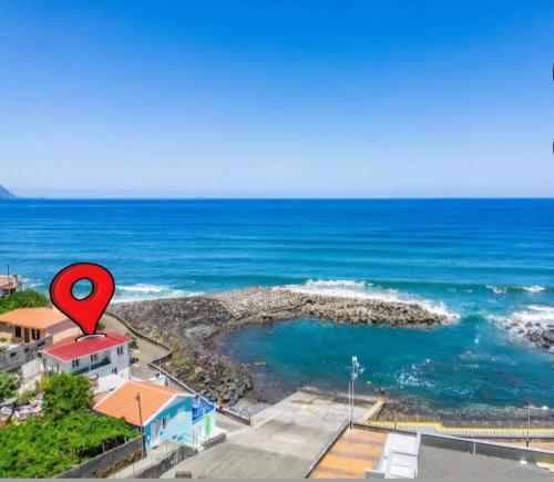 a red marker on top of a house next to the ocean at Casa dos avós in São Vicente