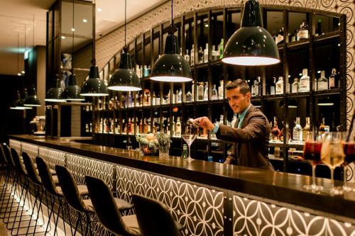 a man standing at a bar making a drink at Motel One Barcelona-Ciutadella in Barcelona