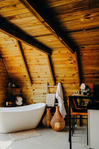 a bathroom with a tub and a wooden ceiling at Olivas Eco Chalé in Pouso Alto