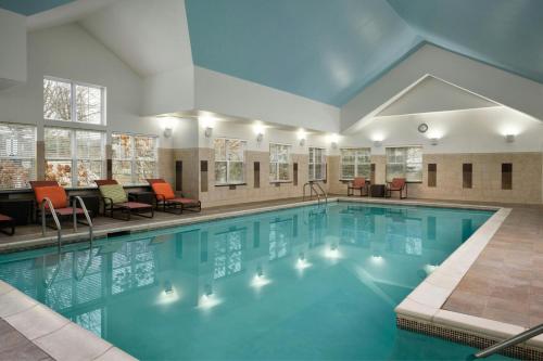 a pool in a hotel with chairs and tables at Residence Inn Burlington Colchester in Burlington