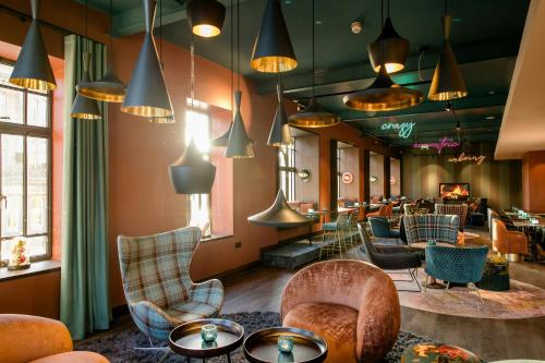 a lobby with chairs and tables and pendant lights at Motel One Edinburgh-Princes in Edinburgh