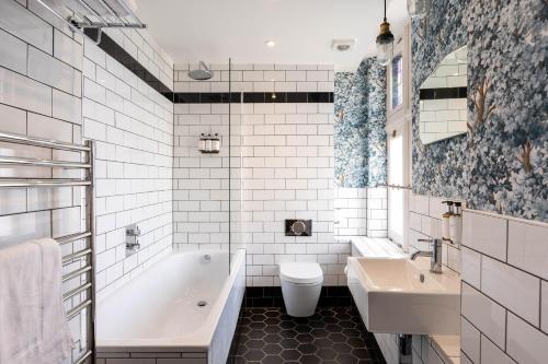a bathroom with a tub and a toilet and a sink at The Red Lion Hotel in London