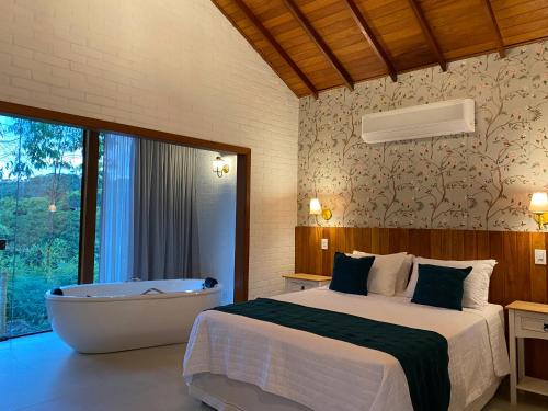 a bedroom with a bed and a bath tub at Chalés Colina dos Colibris in Santa Teresa