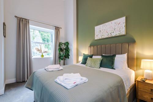 a bedroom with a bed with green walls and a window at Rock Mill - The Penthouse Suite in Stony Middleton