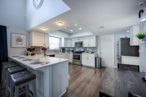 a large kitchen with white cabinets and a large island at Huge Loft Style 3BR - KING Bed, Pool, WiFi, Washer & Dryer, AC, Free Parking -- IDEAL FOR Medical, Business, Groups, Relocation - near Moffitt Cancer Center and Raymond James Stadium -- Centrally Located in Tampa