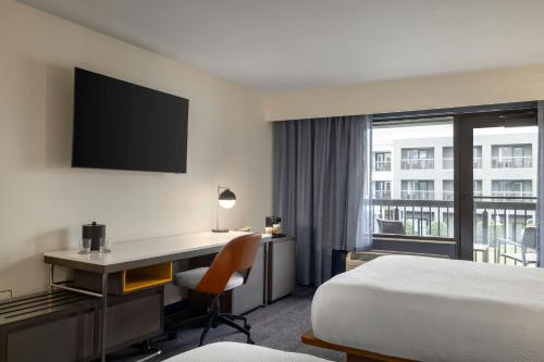 a hotel room with a bed and a desk and a window at Courtyard Fargo Moorhead, MN in Moorhead