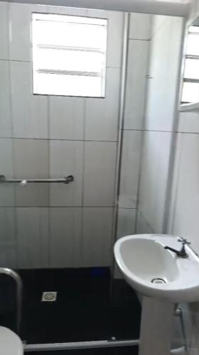 a white bathroom with a sink and a window at Kit 400mts da praia in Bertioga