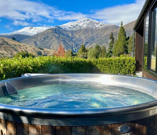 a jacuzzi tub with a view of mountains at The Cottages at Lake Hayes in Queenstown
