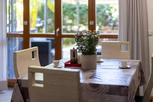 a table with chairs and a vase with flowers on it at HOUSE GARDEN MILANO -Pet Friendly, Giardino Chiuso in Trezzano sul Naviglio