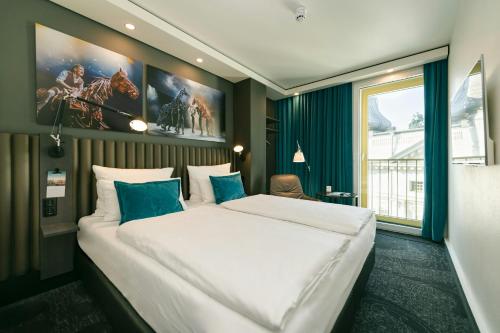 a bedroom with a large white bed with blue pillows at Motel One Berlin-Ku'Damm in Berlin