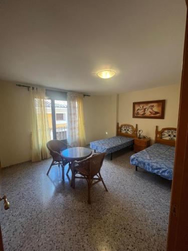 a room with two beds and a table and chairs at Apartamento Pedro de Cella in Cella