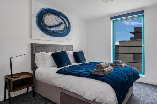 a bedroom with a bed with blue sheets and a window at PENTHOUSE - Spacious, Stunning River Views, Foosball Table, Central, River Front, V&A, Train Station, City Centre, Lift Access, Free Parking & Fully Equipped by SUNRISE LONG LETS and SERVICED ACCOMMODATION DUNDEE - Reduced Mobile App Price in Dundee