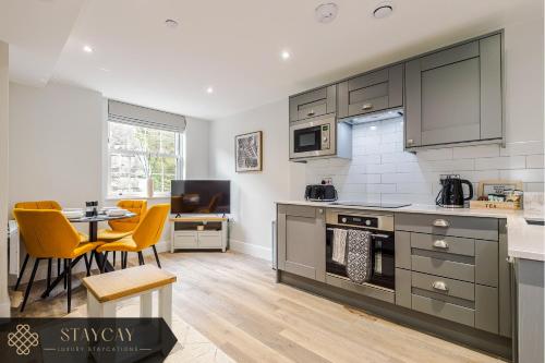 a kitchen with gray cabinets and a table and chairs at Rock Mill - 2-Bedroom Duplex Apartments in Stony Middleton