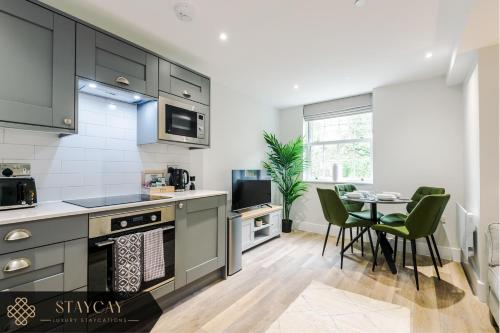 a kitchen with gray cabinets and a table with chairs at Rock Mill - 2-Bedroom Duplex Apartments in Stony Middleton