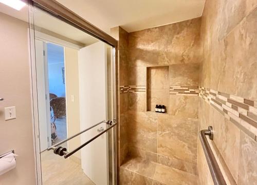 a bathroom with a shower with a glass door at Compass Blue Lahaina in Lahaina
