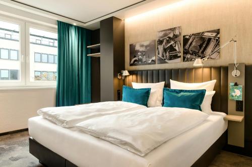 a bedroom with a large white bed with blue pillows at Motel One Frankfurt-East Side in Frankfurt