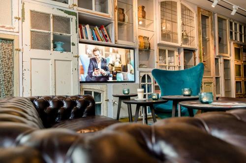 a living room with a couch and tables and a tv at Motel One Amsterdam-Waterlooplein in Amsterdam