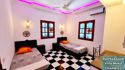 a room with two beds and a checkerboard floor at Villas calme et sans vis-à-vis proche de la plage Tezdaine in Midoun