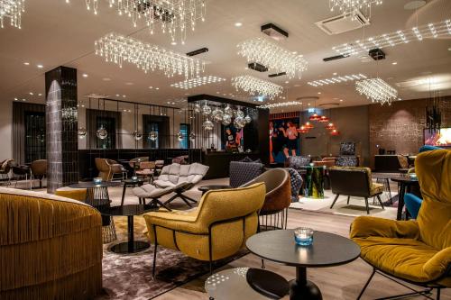 a lobby with chairs and tables and chandeliers at Motel One Berlin-Potsdamer Platz in Berlin